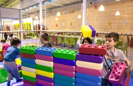Bambini che costruiscono un muro con grandi mattoni morbidi colorati